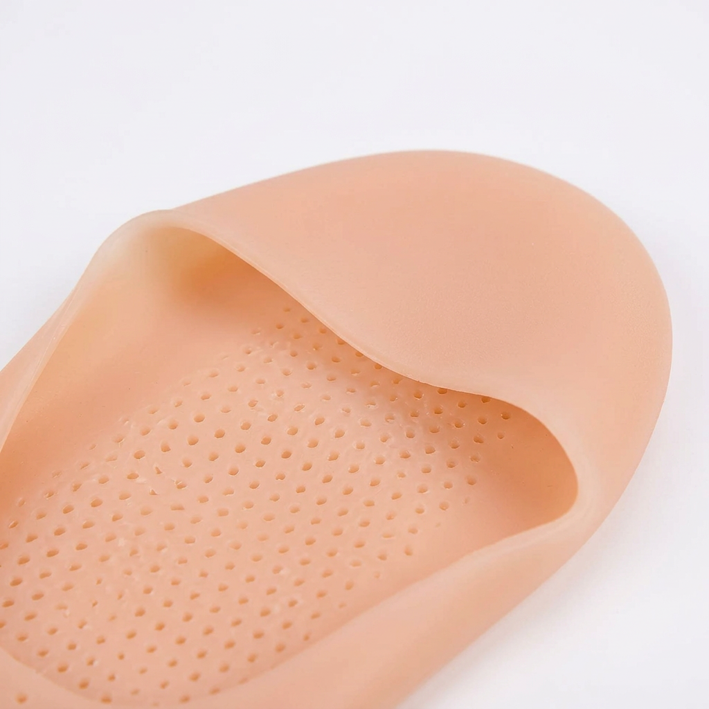 Close-up of small perforations and the smooth edge of a beige silicone gel foot cover